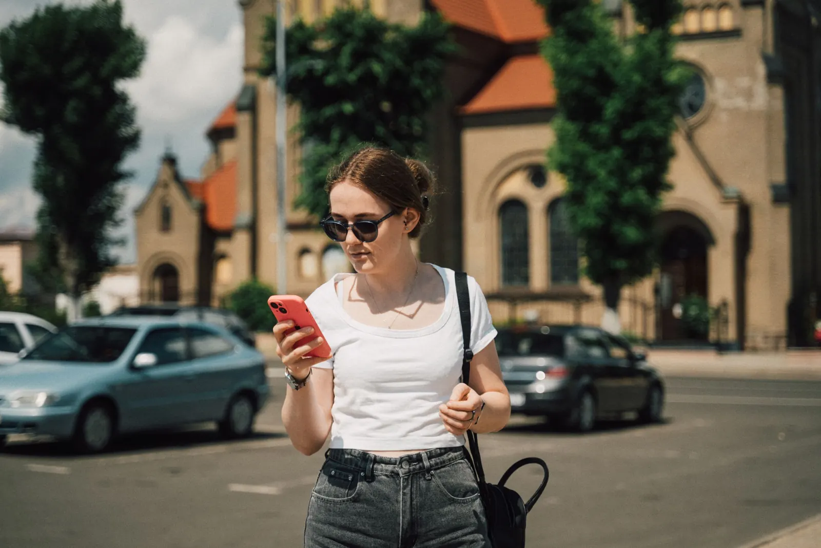 Woman checking her phone next to parked cars